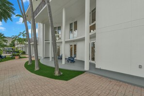 A modern building with a covered outdoor area, palm trees, and a paved walkway. - The Coral Cove Chic 1BR Condo Shore Diving 302 (Fort Lauderdale)