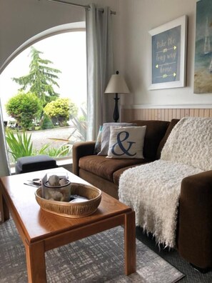 Un salon chaleureux avec un canapé marron, un plaid blanc et une table basse en bois sur laquelle repose un bol décoratif.