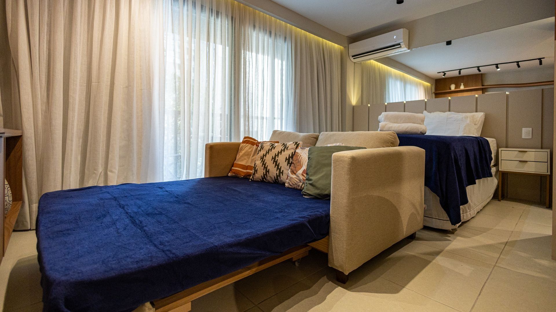 A modern bedroom with a single bed, a sofa bed, and a small table.