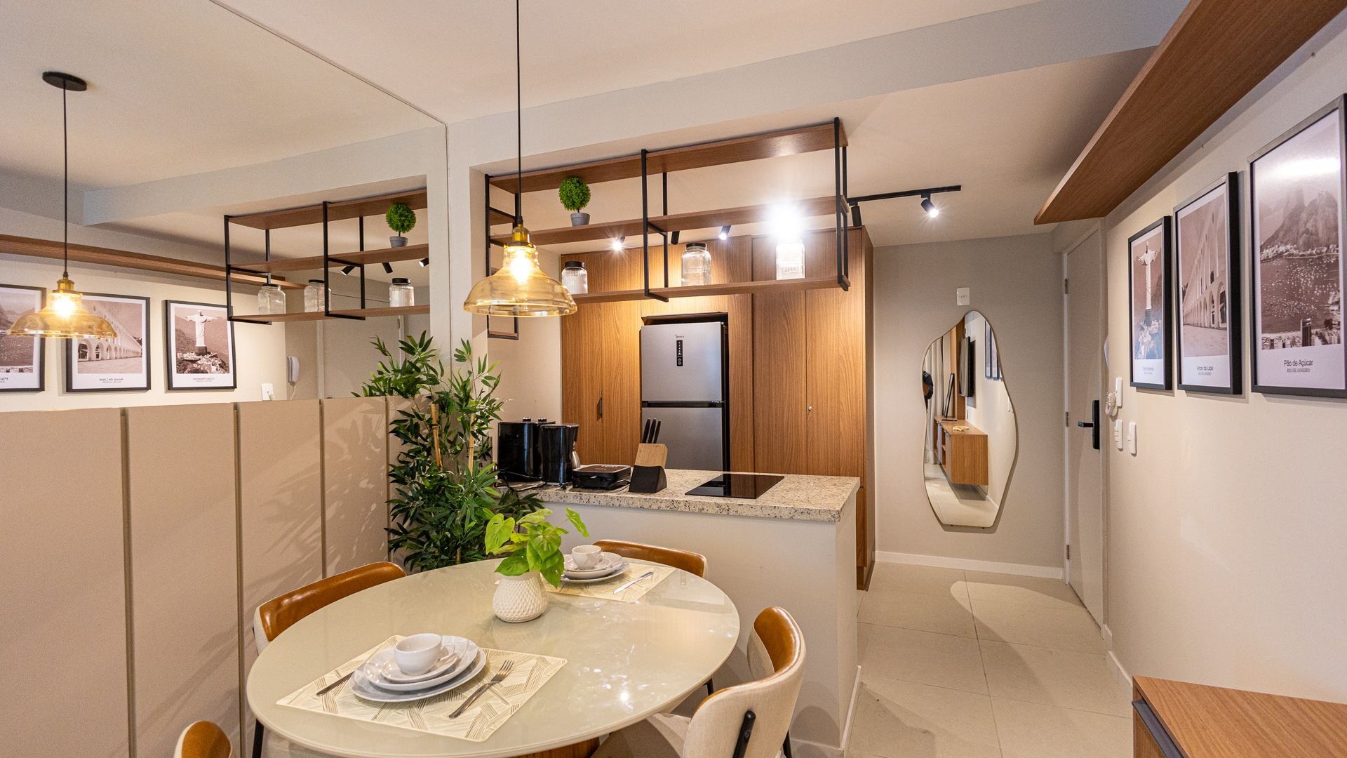 A modern kitchen with wooden cabinetry, a built-in refrigerator, and a dining area with a round table and chairs.