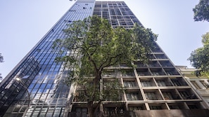 A tall building with a glass facade and a tree in the foreground. - Skylux Downtown Rio With Rooftop Pool, Coworking Space, Gym, and Easy Access to the Subway by Carpediem (Rio de Janeiro)