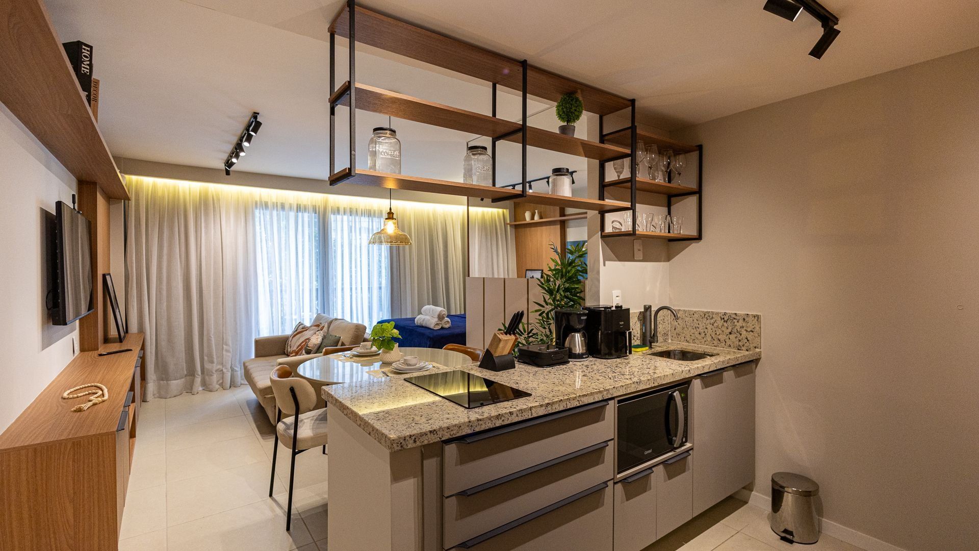 A compact kitchen with a central island, built-in shelves, and a dining area with a sofa and table.