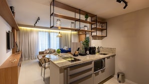 A compact kitchen with a central island, built-in shelves, and a dining area with a sofa and table. - Skylux Downtown Rio With Rooftop Pool, Coworking Space, Gym, and Easy Access to the Subway by Carpediem (Rio de Janeiro)
