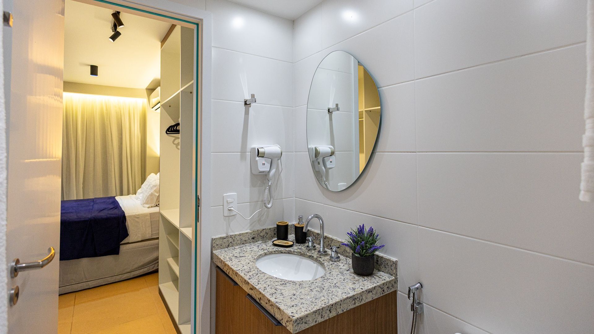 A hotel bathroom with a sink, mirror, hairdryer, and towel rack.