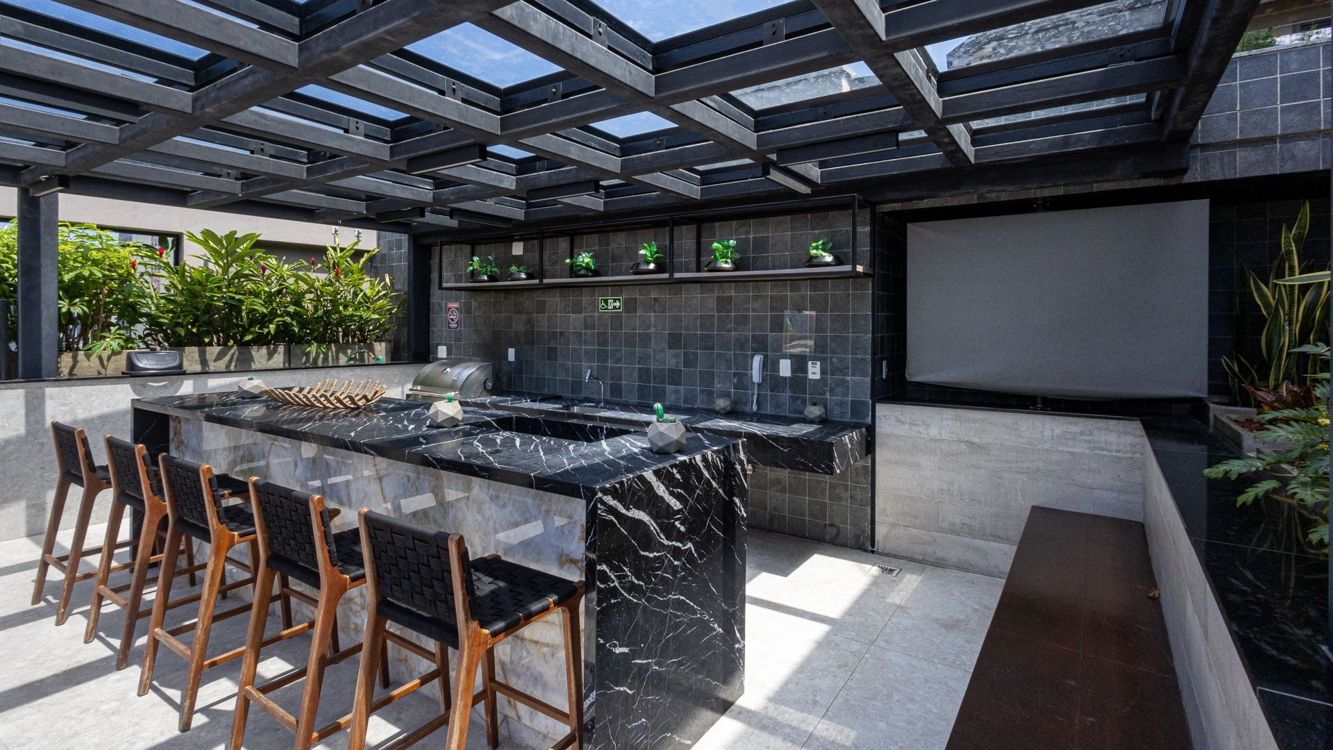 An outdoor kitchen area with a marble countertop, bar stools, and a grill.