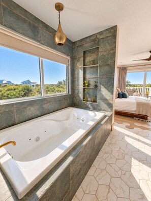 Ein modernes Badezimmer mit einer großen Badewanne, einem Fenster mit Blick und einem Deckenventilator.
