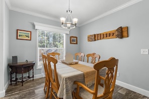 A dining room with a wooden table, chairs, a chandelier, and artwork on the walls. - Fin & Feather - Steinhatchee Florida (Steinhatchee)