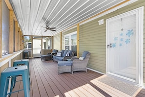 A covered outdoor area with a ceiling fan, a seating area with a sofa and chairs, and a door with a turtle decal. - Fin & Feather - Steinhatchee Florida (Steinhatchee)
