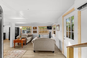 A spacious living room with a sofa, a coffee table, and a TV. - Island Time Bungalow - Home in Steinhatchee (Steinhatchee)