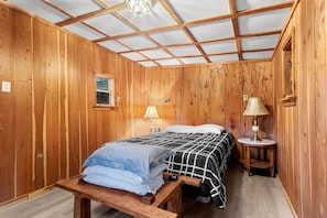 A wooden-paneled room with two beds, a bench, a small table, and a window. - Island Time Bungalow - Home in Steinhatchee (Steinhatchee)