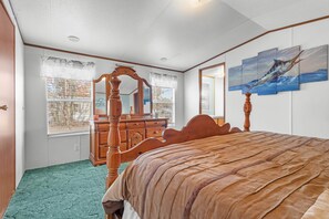 Een slaapkamer met een hemelbed, een dressoir, een spiegel en kunstwerken aan de muur.