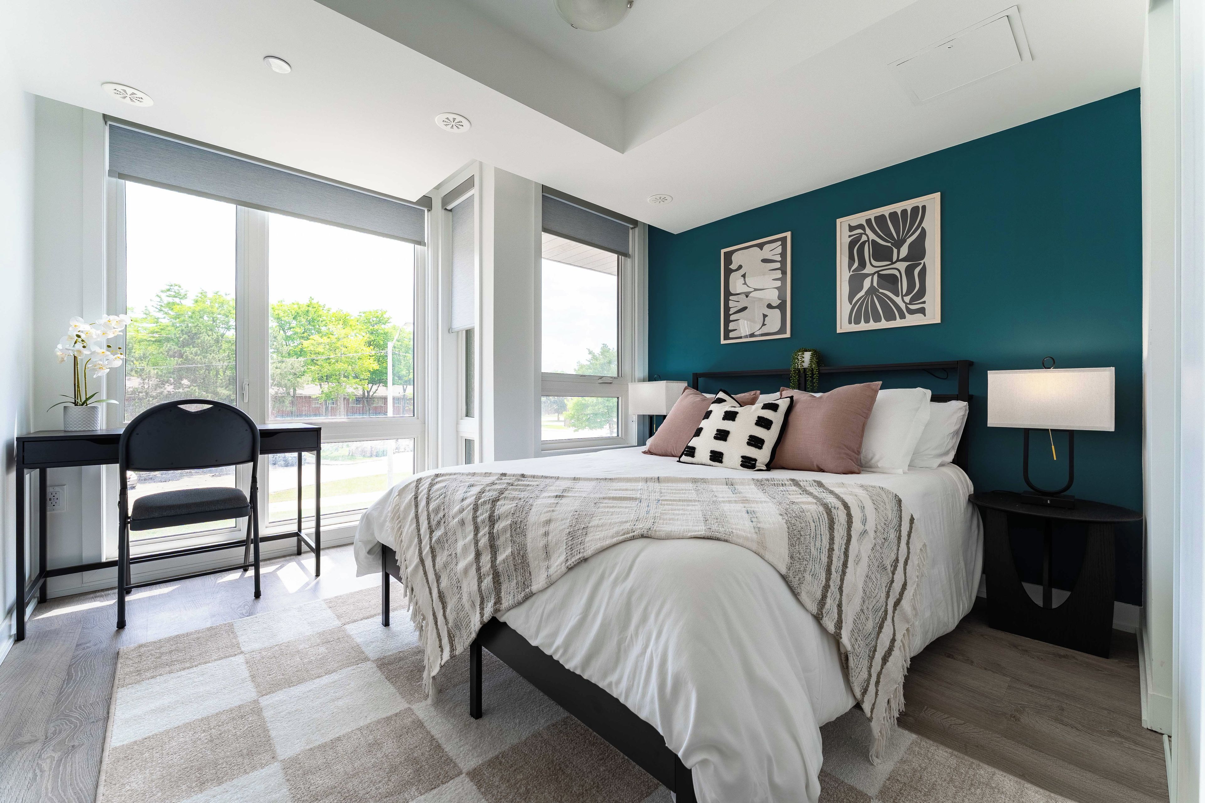 A bedroom with a bed, a desk, and a chair.