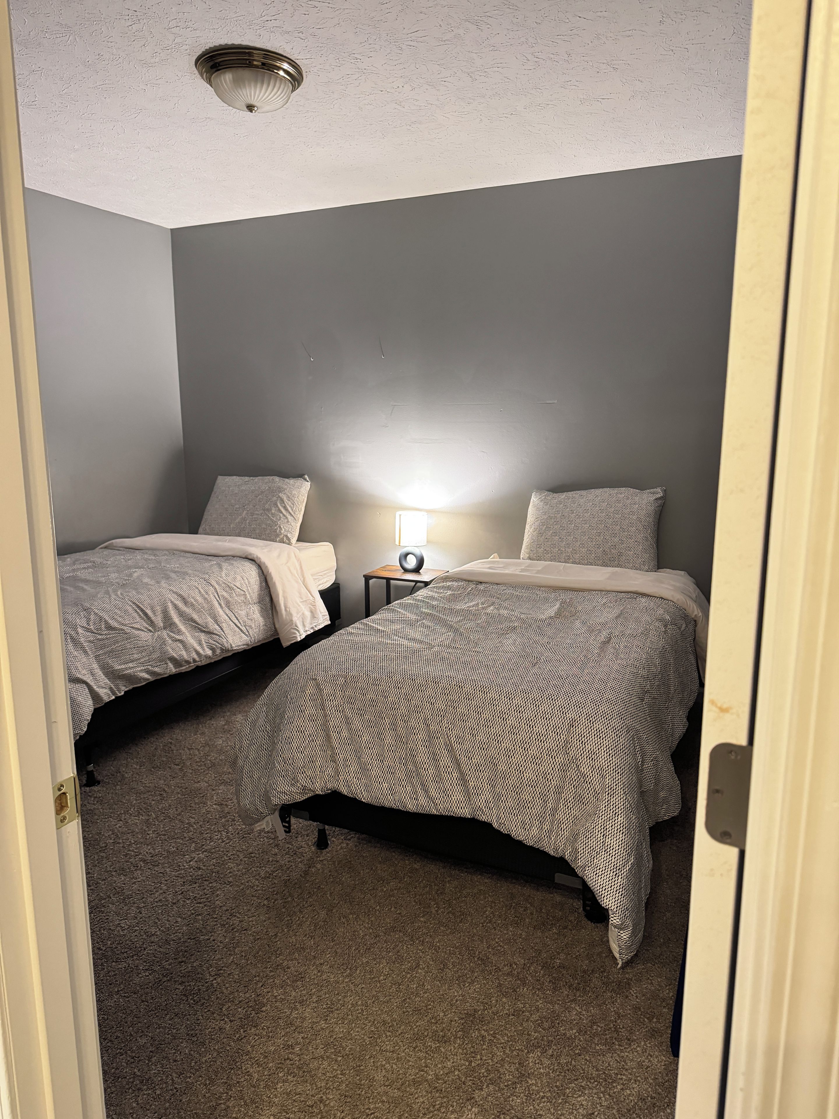 Ein Schlafzimmer mit zwei Betten, einem Nachttisch, einer Lampe und einer Deckenleuchte.