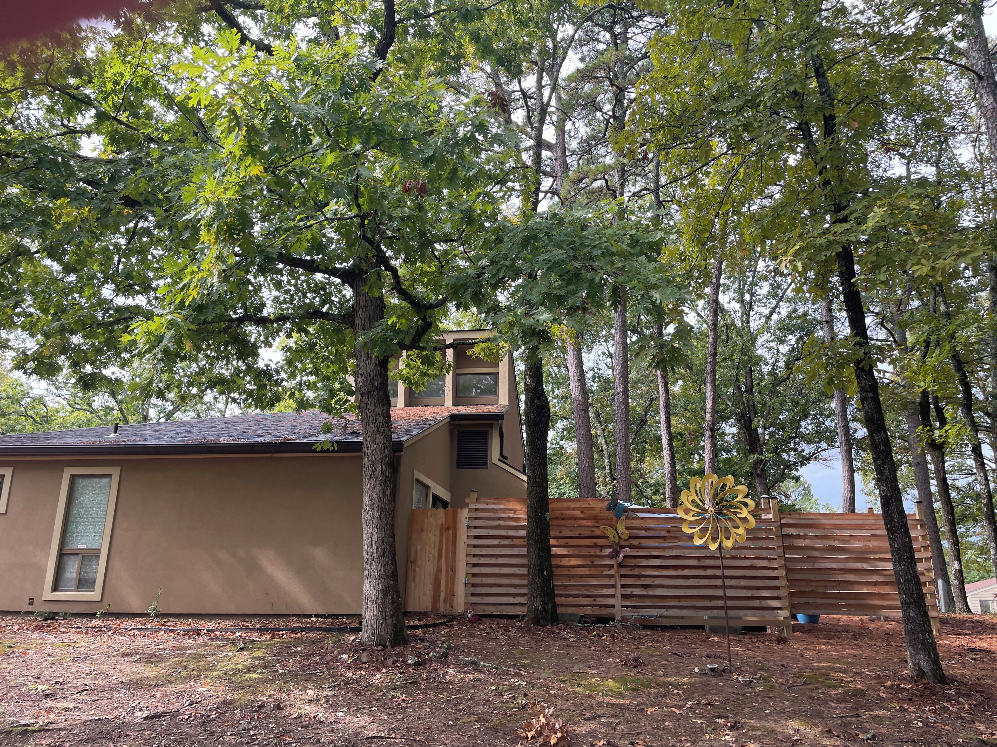 Una propiedad residencial con una casa, cerca de una valla de madera y un árbol grande.
