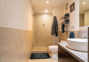 Een moderne badkamer met douche, toilet en wastafel.