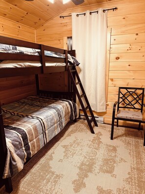 Ett rum med en våningssäng, en stege, en stol och en gardin.