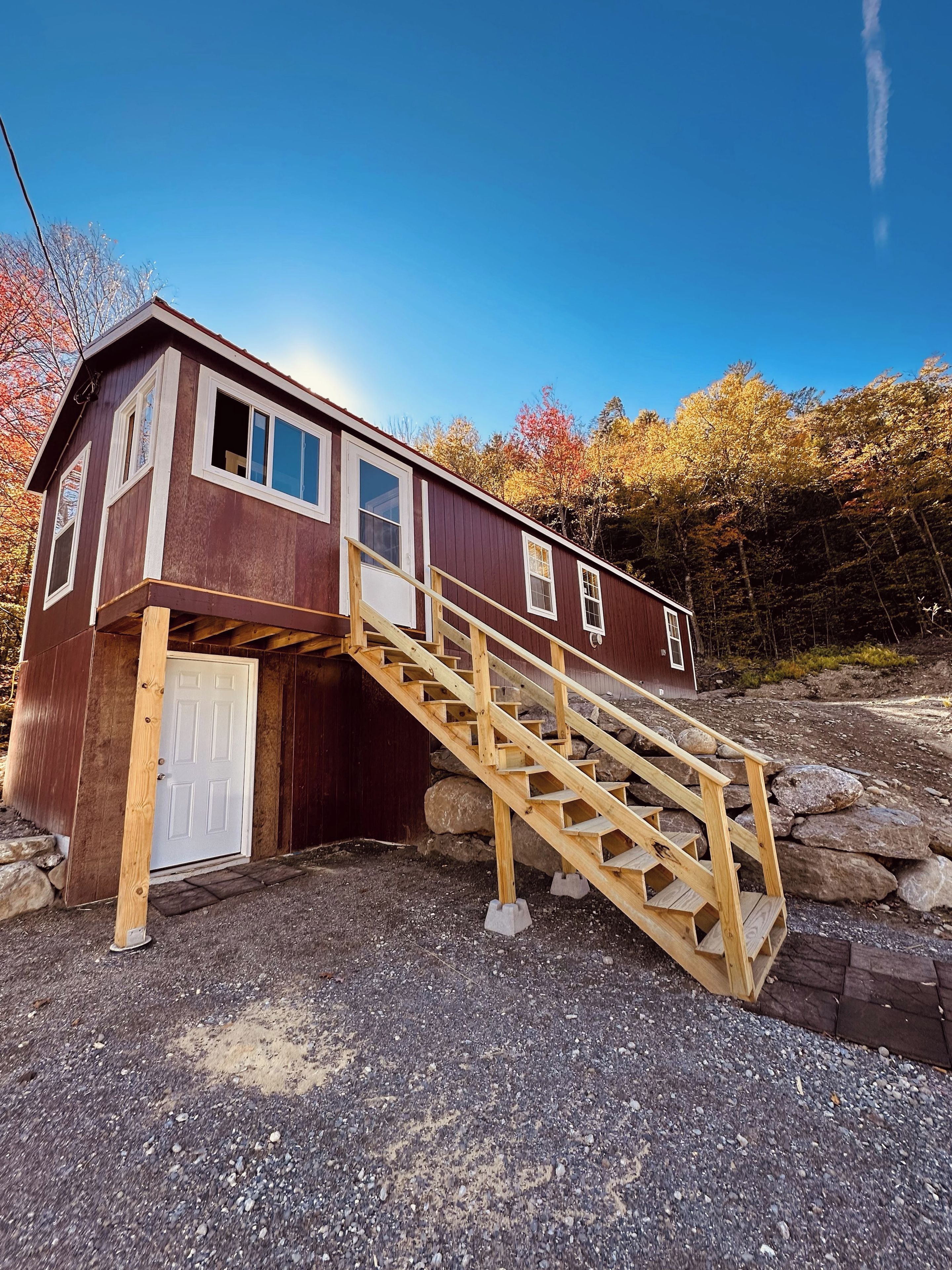 A wooden cabin with a wooden staircase leading to a door.