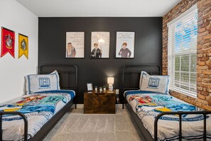 Een slaapkamer met twee bedden, een nachtkastje en drie posters aan de muur.