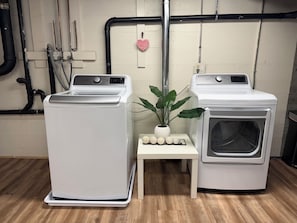 Dues rentadores frontals blanques, una taula petita amb una planta en maceta, i una decoració de cor rosa a la paret.