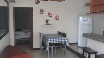 Un espacio habitable compacto con una mesa de comedor, sillas, un sofá, un refrigerador y una encimera de cocina.