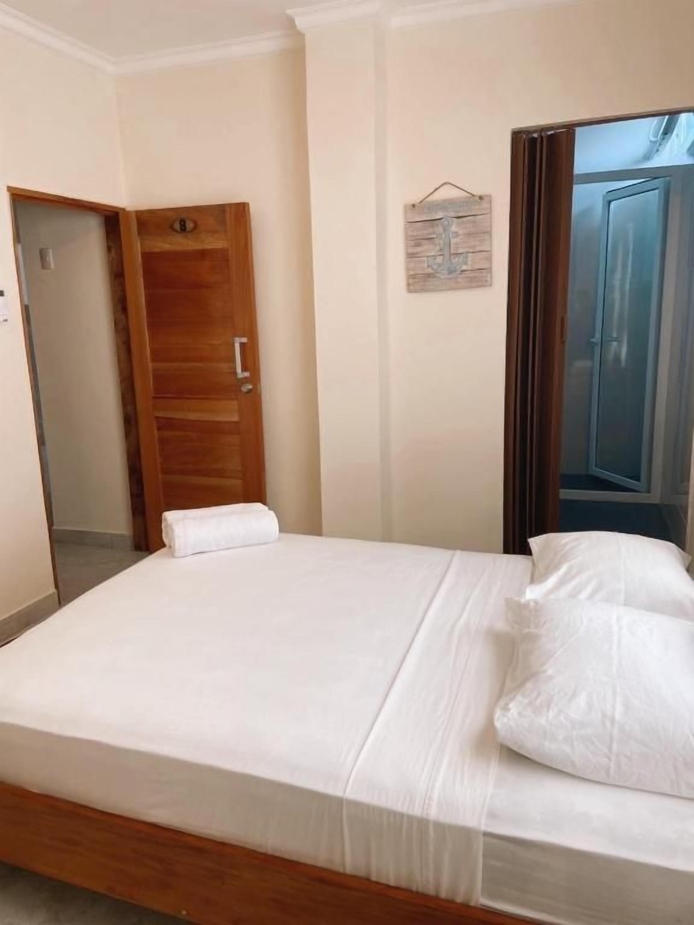 A hotel room with a wooden bed, a door, and a wall-mounted sign.
