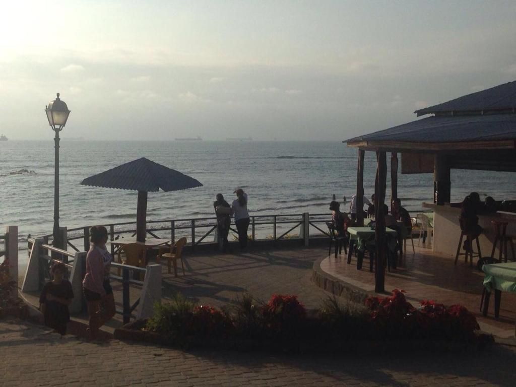 An outdoor seating area with tables and chairs, overlooking a body of water.