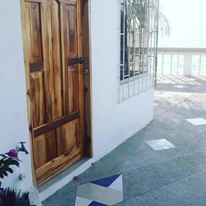 A wooden door with a metal gate, a white wall, and a tiled floor with a geometric pattern.