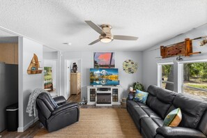 A living room with a sofa, a recliner, a fireplace, a TV, and a ceiling fan. - Wildwood Angler's Getaway - Steinhatchee Florida (Steinhatchee)