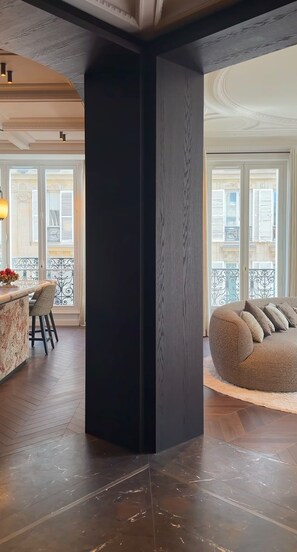Een ruime woonkamer met een donkere accentmuur, een ronde zithoek en uitzicht op het buitenbalkon.
