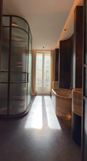 Een modern interieur met een gebogen zithoek, een glazen scheidingswand en uitzicht op het omliggende landschap.