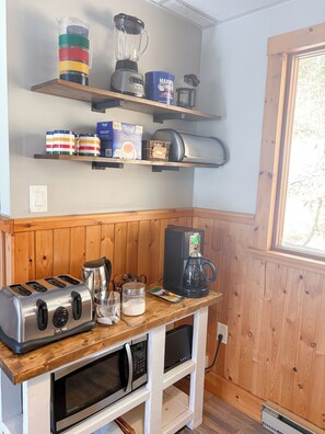 A kitchen with wooden cabinets, a coffee maker, a toaster, a blender, and various kitchen utensils. - Baptiste Lake House In Bancroft- Waterfront- Pet Friendly (Hastings Highlands)