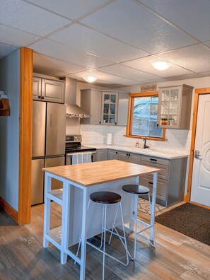 A compact kitchen with a central island, stainless steel appliances, and a window with a view. - Baptiste Lake House In Bancroft- Waterfront- Pet Friendly (Hastings Highlands)