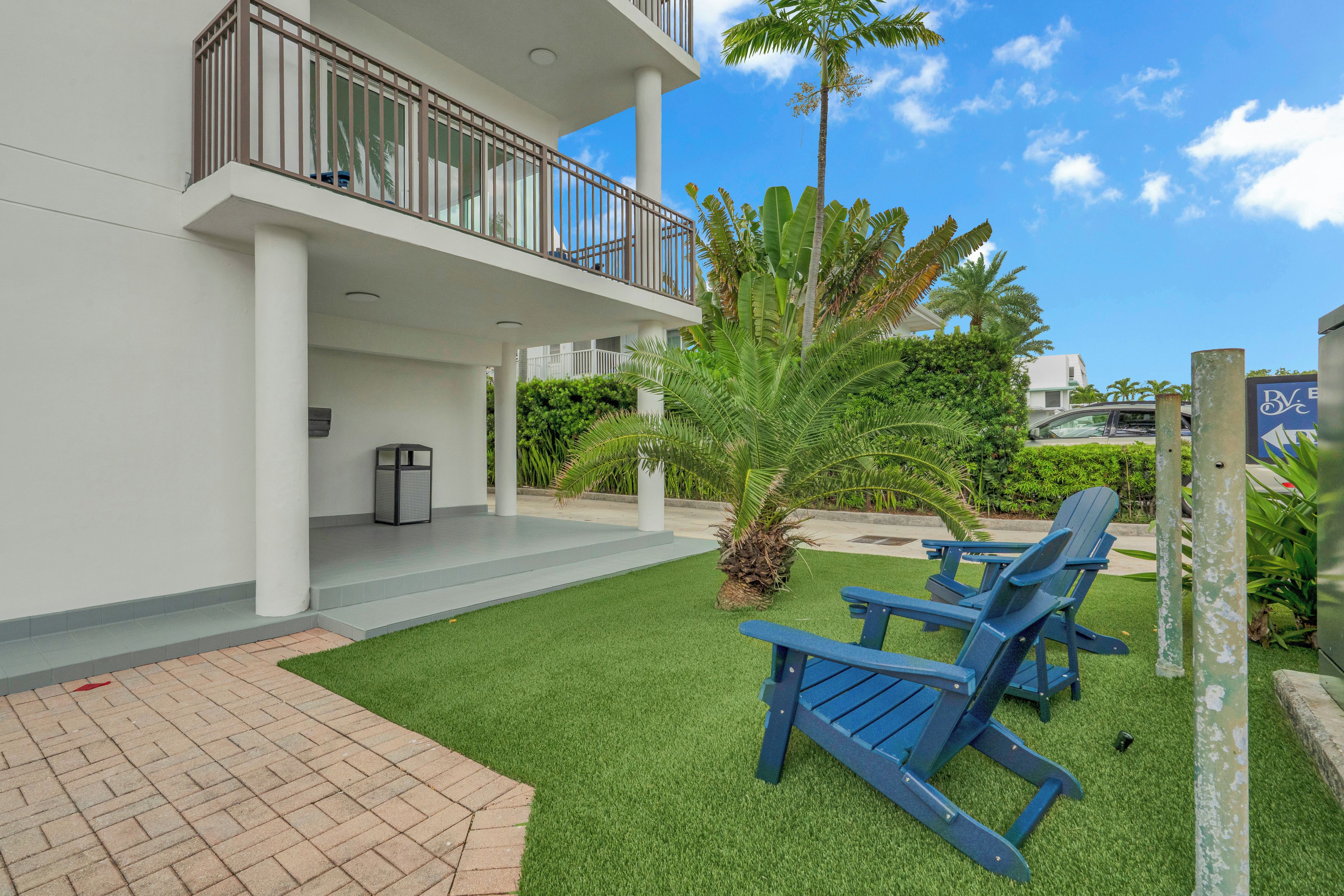 A modern building with a balcony, outdoor seating, and a well-maintained lawn.