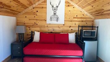 A room with a bed, a nightstand, a lamp, a microwave, and a poster on the wall.