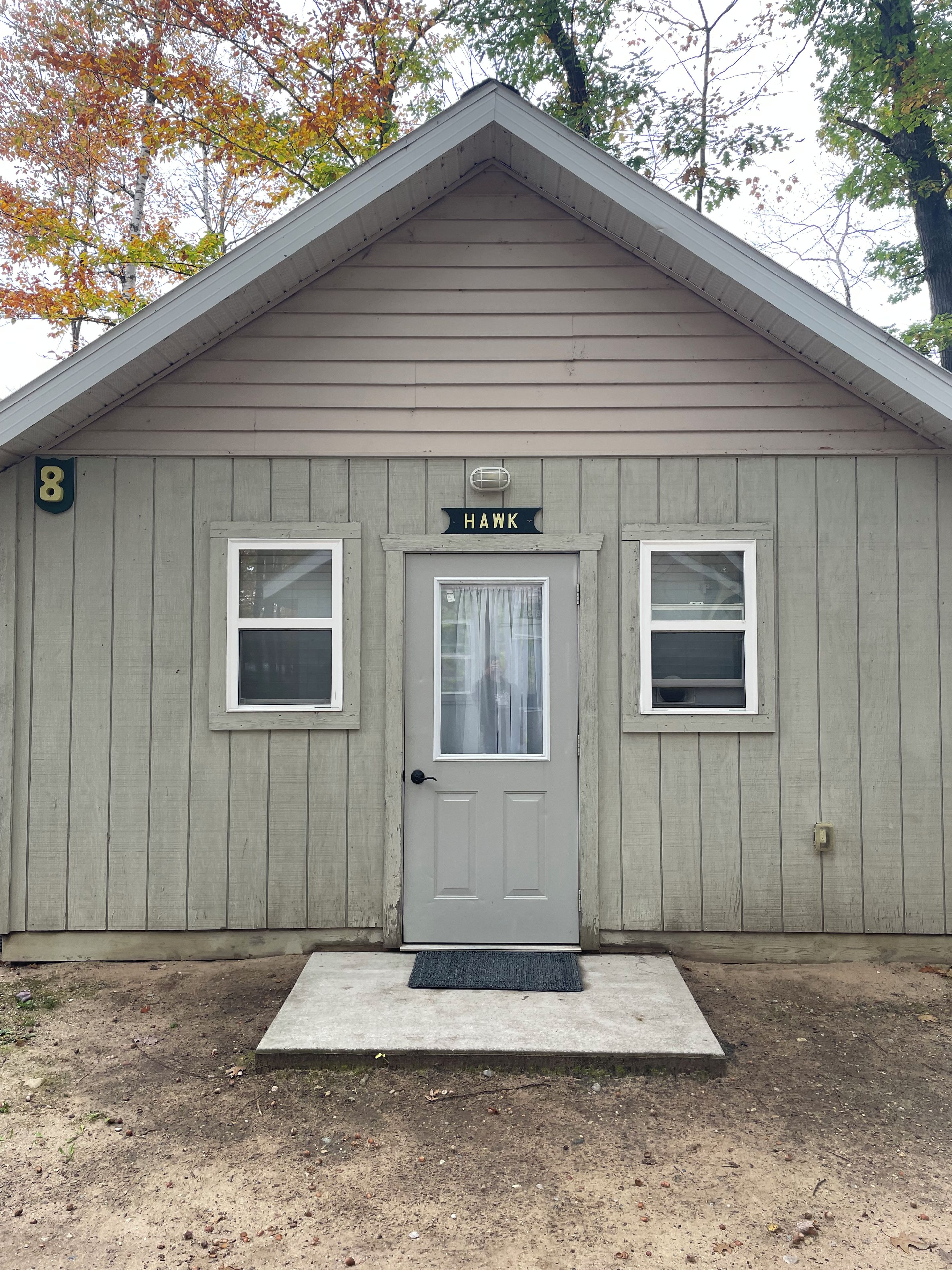 A single-story building with a gabled roof, a front door, and two windows on either side.