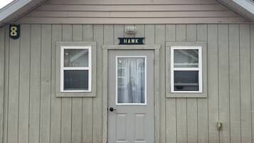 A single-story building with a gabled roof, a front door, and two windows on either side.