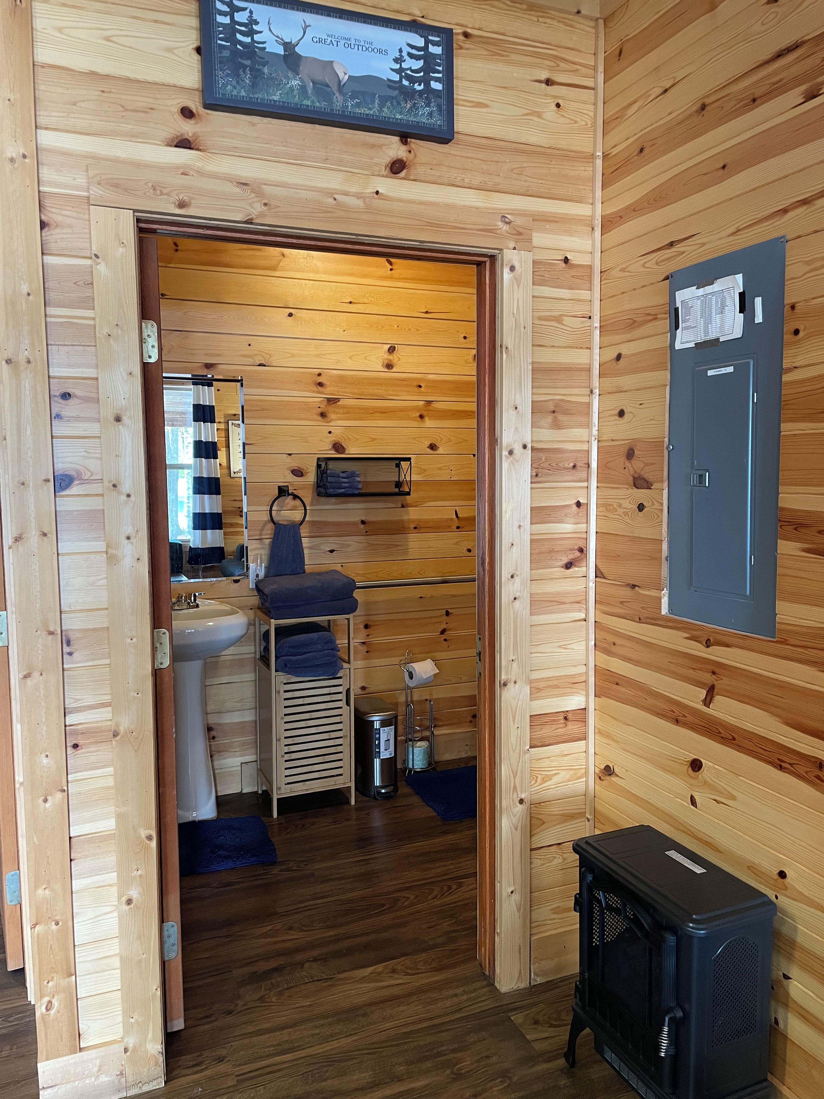 A wooden interior with a sink, towel rack, and a black heater.