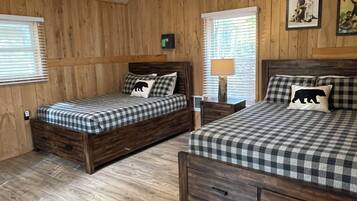 Un dormitorio con dos camas de madera, un ventilador de techo y paredes de madera.