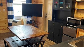 A wooden interior with a dining table, black cabinets, a microwave, and a sign reading 'LAKE HOUSE'.