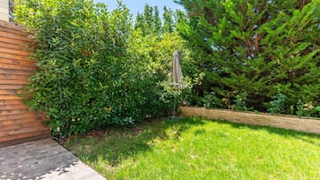Un jardín bien cuidado con un sendero de piedra, follaje denso y una valla de madera.
