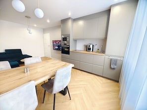 Una cocina moderna con una mesa de madera, sillas y electrodomésticos integrados.