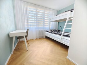 Ein Zimmer mit einem Etagenbett, einem Schreibtisch und einem Stuhl.