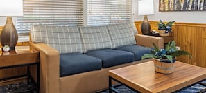En hyggelig opholdsstue med sofa, to sofaborde, en lampe og en potteplante.