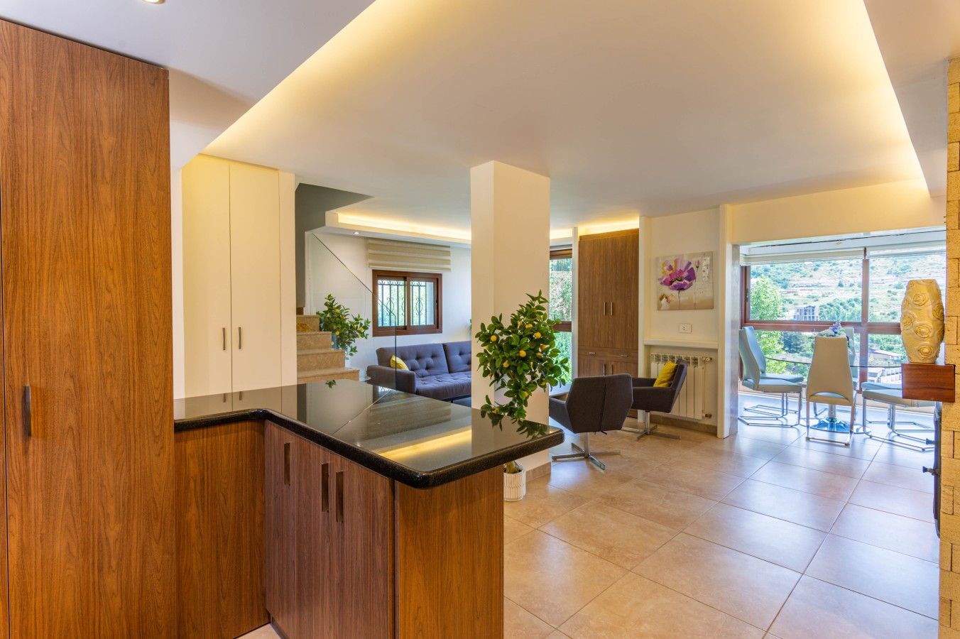 Una cocina moderna con armarios de madera, encimera negra y un comedor con mesa y sillas.