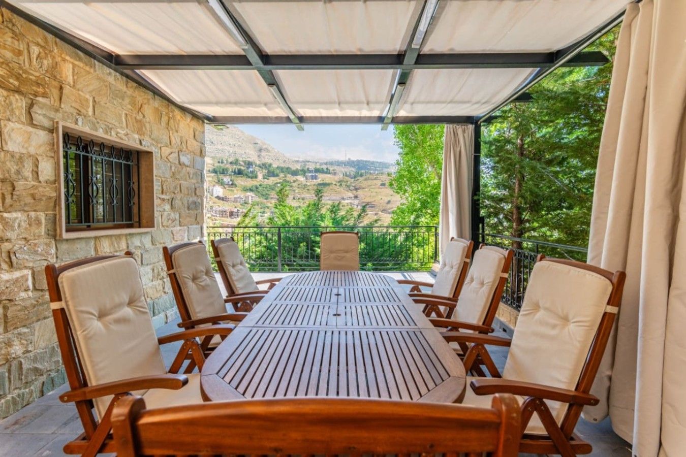 Un espacio de comedor al aire libre cubierto, con pared de piedra, una mesa y seis sillas.