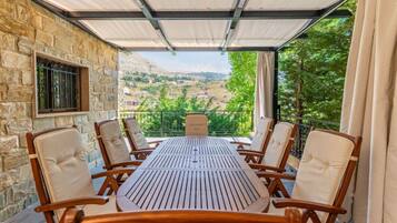 Un espacio de comedor al aire libre cubierto, con pared de piedra, una mesa y seis sillas.