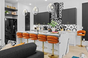 A modern kitchen with a central island, bar stools, and pendant lighting. - 10 Min to Broadway-Rooftop Hangout-Garage Parking (Nashville)