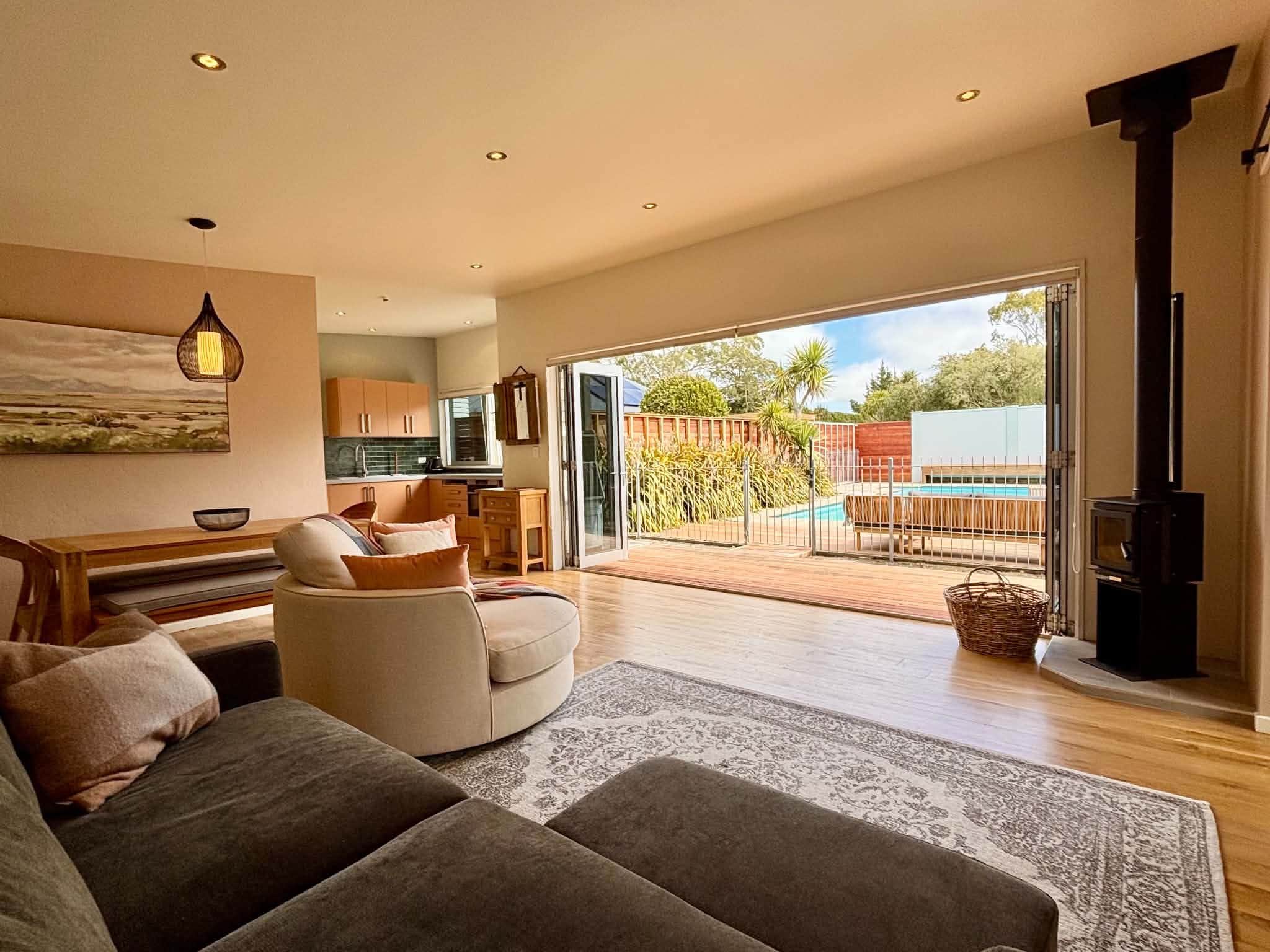 Una sala de estar moderna con un sofá, un comedor y vistas a una piscina y jardín.