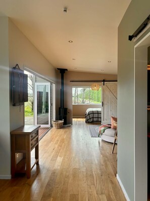 Una habitación amplia con piso de madera, un ventanal grande, un televisor y una escalera que sube a otro nivel.