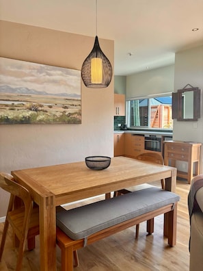 Comedor con mesa de madera, banco y lámpara colgante.